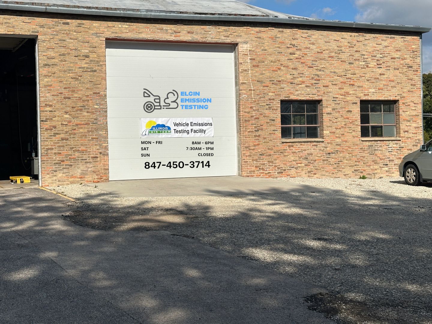 Elgin Emission Testing Station facility exterior — Vehicle Emissions Testing Facility sign on garage door