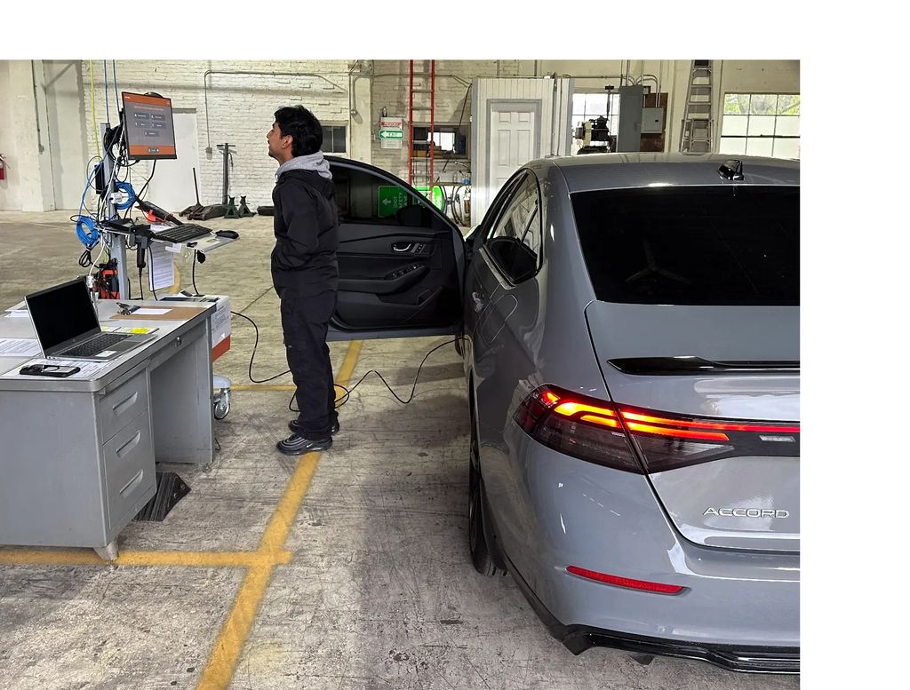 Technician performing vehicle emissions test at Elgin Emission Testing Station
